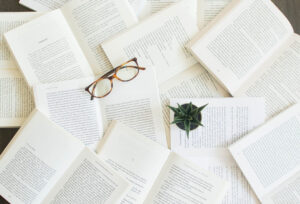 multiple books, eyeglasses strewn about