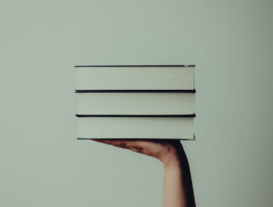 hand holding up a stack of books